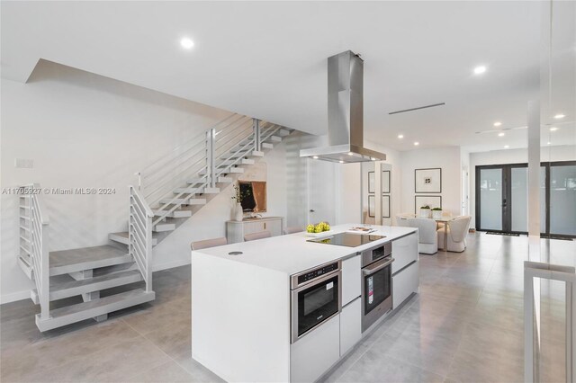 kitchen featuring island exhaust hood, white cabinetry, black electric stovetop, and oven