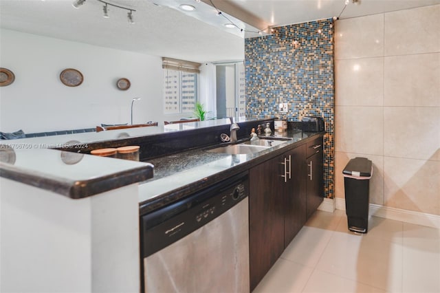 kitchen with dark brown cabinetry, stainless steel dishwasher, tile walls, and sink