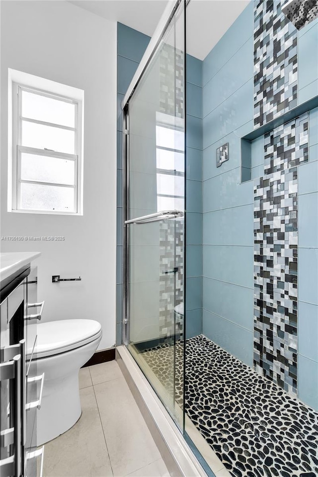 bathroom featuring vanity, a shower with door, tile patterned flooring, and toilet