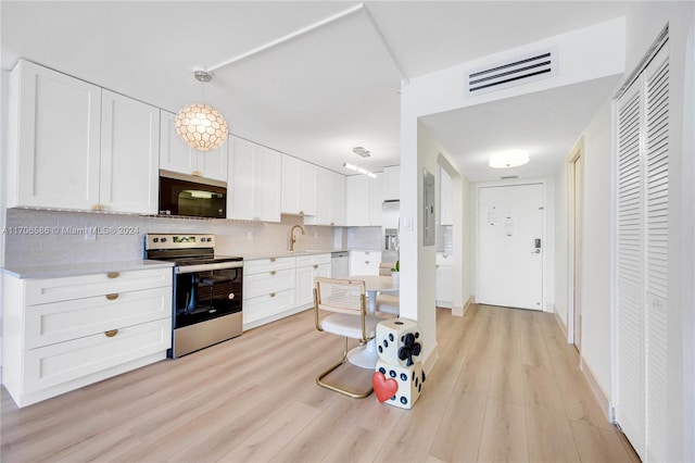 kitchen featuring light hardwood / wood-style flooring, backsplash, decorative light fixtures, white cabinets, and appliances with stainless steel finishes