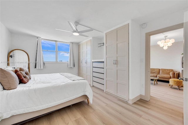 bedroom with ceiling fan with notable chandelier and light wood-type flooring