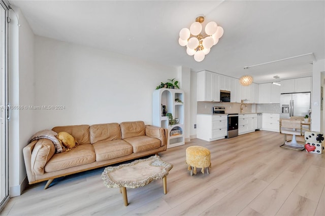 living room with an inviting chandelier, light hardwood / wood-style flooring, and sink