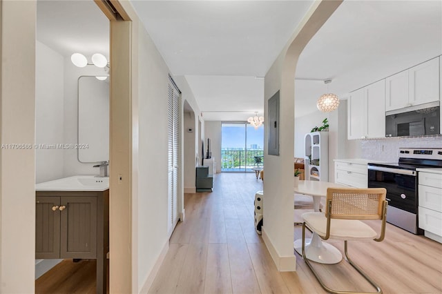 kitchen featuring white cabinets, sink, hanging light fixtures, light wood-type flooring, and stainless steel appliances