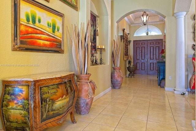 entryway with an inviting chandelier, ornamental molding, and light tile patterned flooring