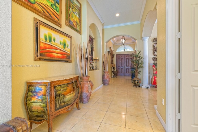 hallway with decorative columns, crown molding, and light tile patterned floors