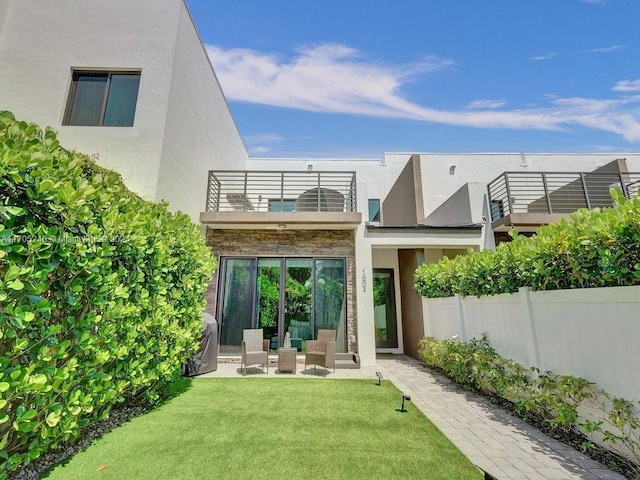 rear view of property featuring a yard, a balcony, and a patio area