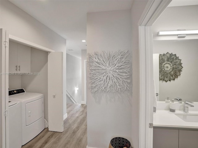 laundry room featuring washing machine and dryer, sink, and light hardwood / wood-style flooring