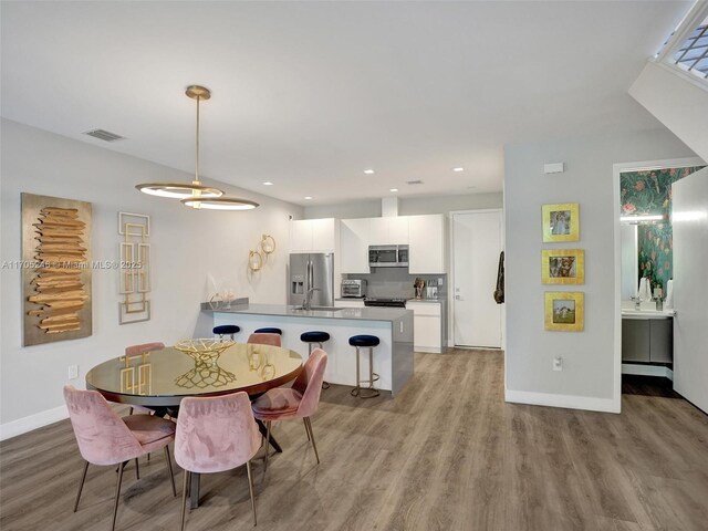 kitchen featuring white cabinets, sink, stainless steel dishwasher, dark hardwood / wood-style floors, and decorative light fixtures