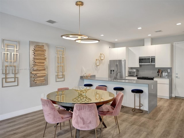 dining space with sink and light hardwood / wood-style flooring