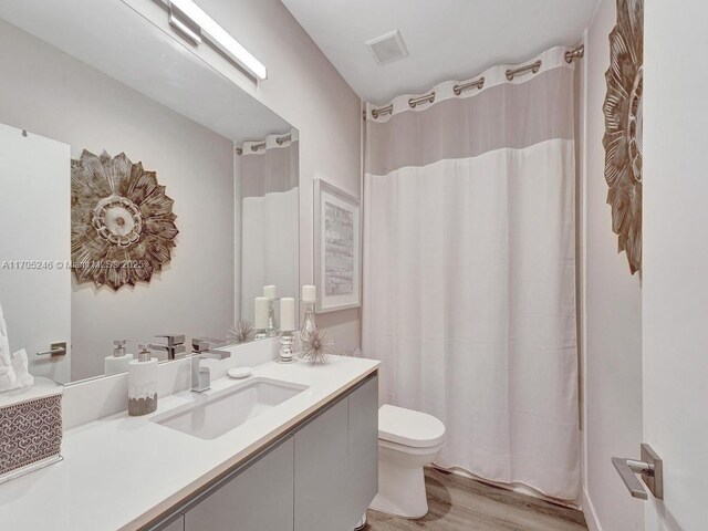 bathroom with walk in shower, toilet, vanity, and hardwood / wood-style flooring