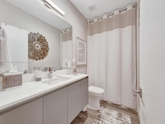 bathroom featuring wood-type flooring, vanity, toilet, and curtained shower