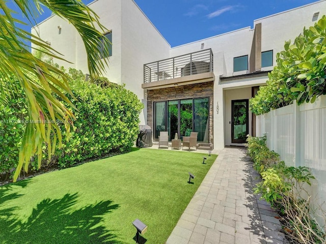 back of house featuring a balcony and a lawn