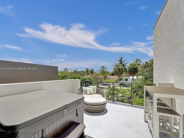 view of patio / terrace with a balcony and a hot tub