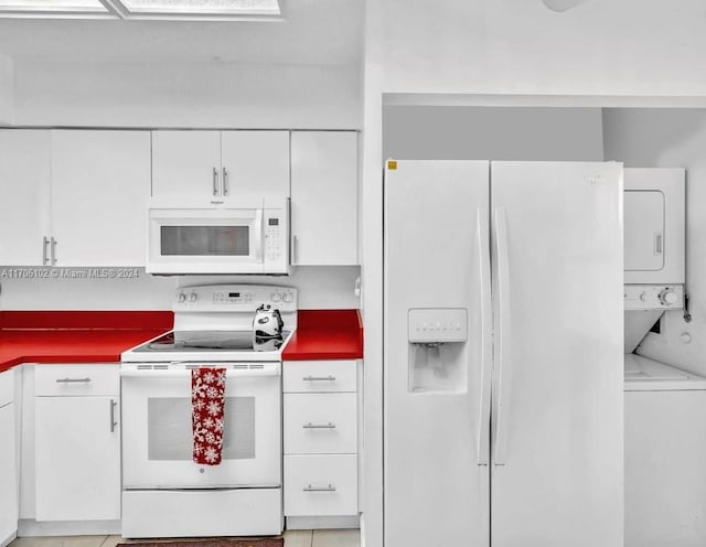 kitchen featuring light tile patterned floors, white appliances, stacked washer and dryer, and white cabinetry