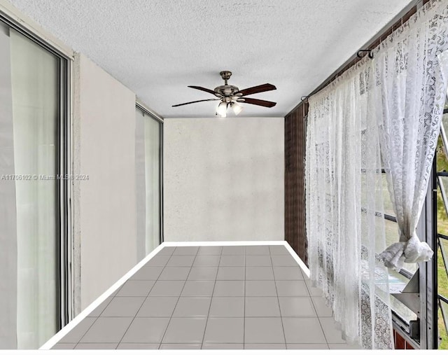 tiled empty room featuring ceiling fan and a textured ceiling