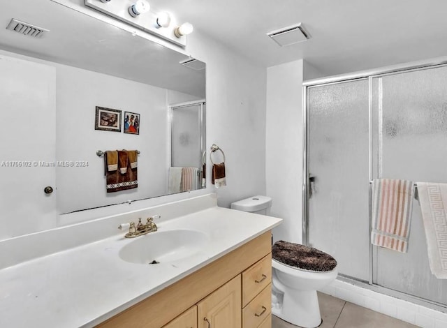 bathroom featuring toilet, vanity, tile patterned floors, and a shower with shower door