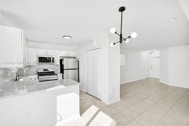 kitchen featuring white cabinets, sink, hanging light fixtures, appliances with stainless steel finishes, and kitchen peninsula