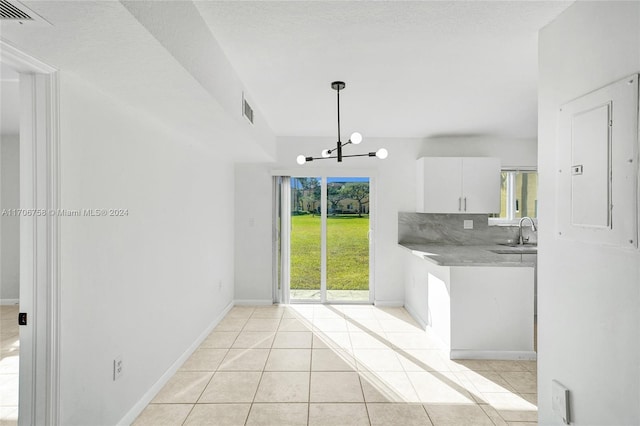 kitchen with sink, light tile patterned floors, decorative light fixtures, electric panel, and white cabinetry