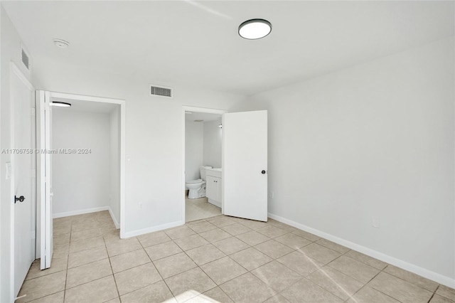 unfurnished bedroom with light tile patterned floors and connected bathroom