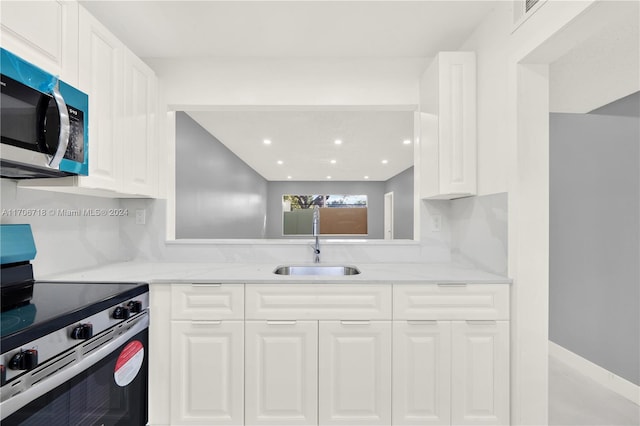 kitchen with white cabinets, stainless steel appliances, light stone countertops, and sink