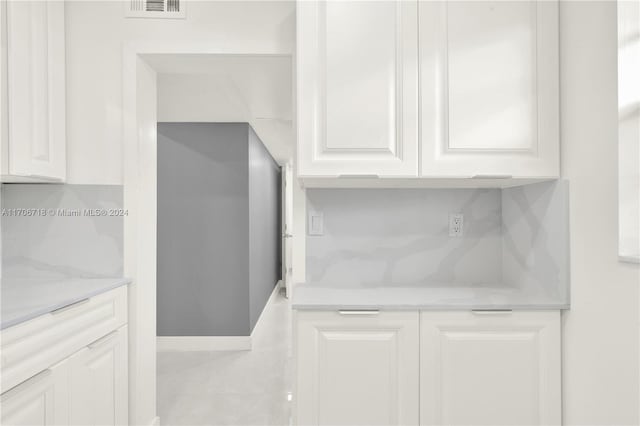 kitchen with decorative backsplash, light stone countertops, and white cabinets