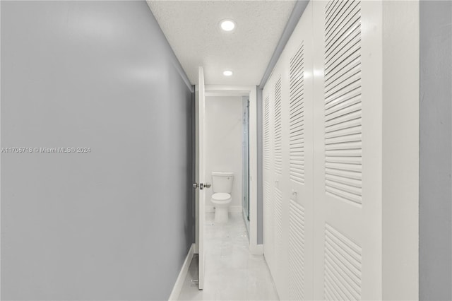 corridor featuring light tile patterned floors and a textured ceiling