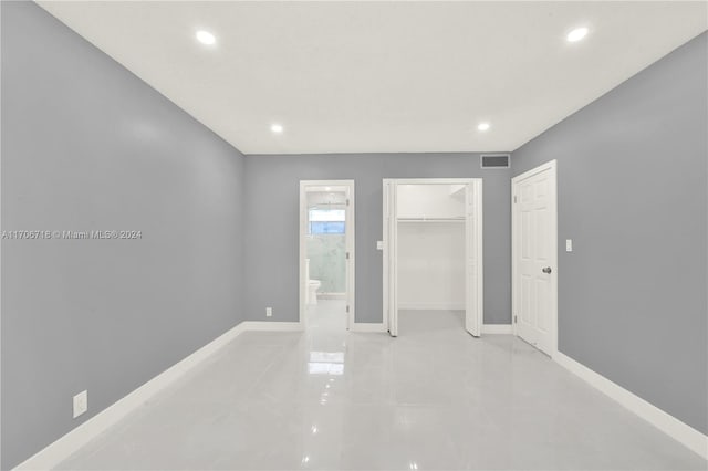 unfurnished bedroom featuring light tile patterned flooring and ensuite bath