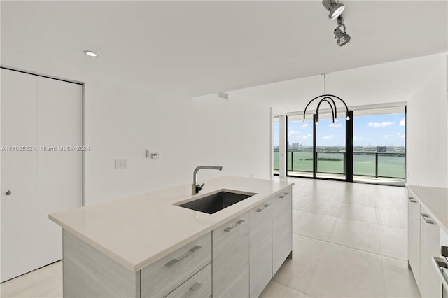 kitchen featuring decorative light fixtures, a center island with sink, white cabinetry, and sink