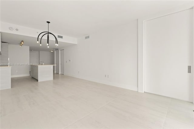 unfurnished living room with light tile patterned floors and a chandelier