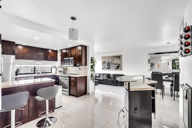 kitchen featuring a center island, light tile patterned floors, hanging light fixtures, and appliances with stainless steel finishes