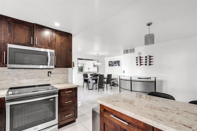 kitchen with decorative backsplash, light stone counters, stainless steel appliances, light tile patterned floors, and pendant lighting