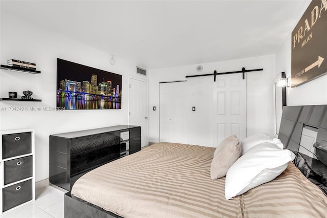 bedroom featuring a barn door, a closet, and light tile patterned floors