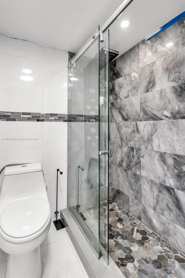 bathroom with a shower with door, tile patterned flooring, tile walls, and toilet