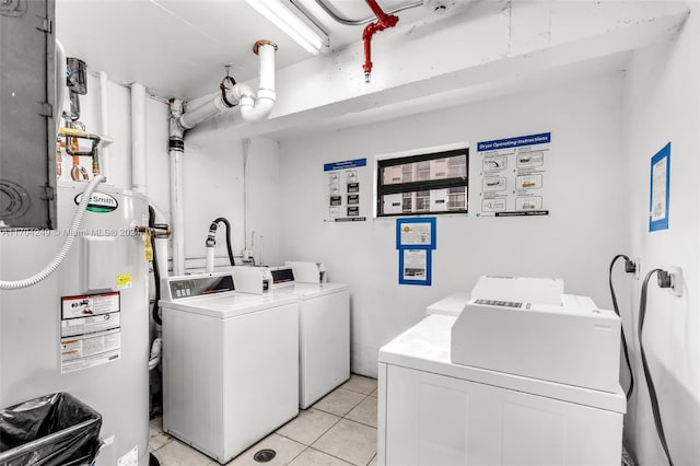 clothes washing area with gas water heater, independent washer and dryer, and light tile patterned floors