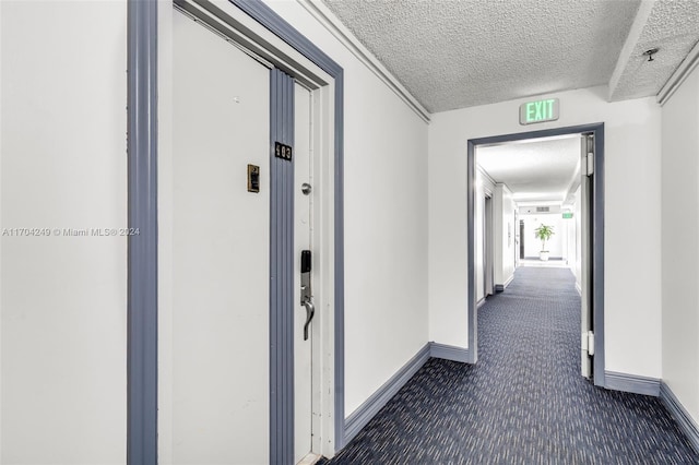 hallway featuring dark colored carpet and a textured ceiling