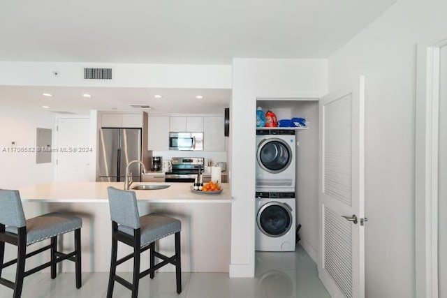 washroom with stacked washer / drying machine and sink