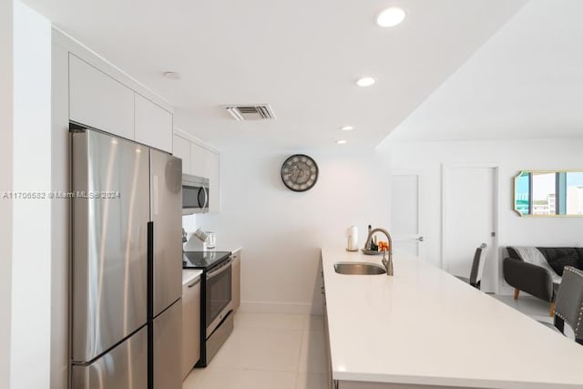 kitchen featuring sink, white cabinets, stainless steel appliances, and light tile patterned floors