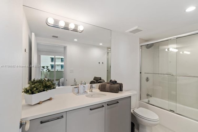 full bathroom featuring vanity, enclosed tub / shower combo, and toilet