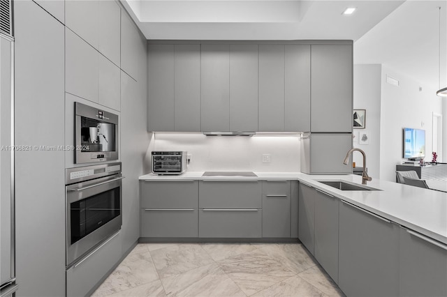 kitchen with cooktop, gray cabinetry, and sink