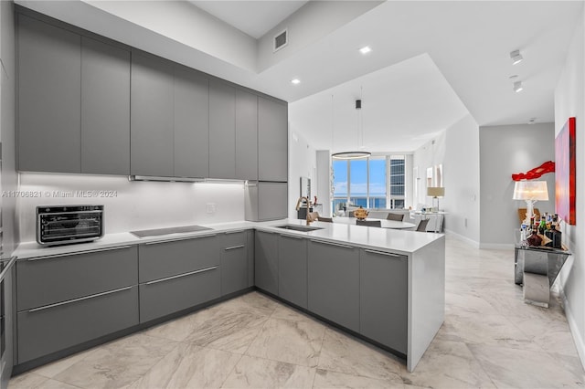 kitchen featuring kitchen peninsula, black cooktop, sink, and gray cabinetry