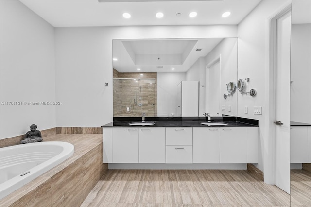 bathroom featuring plus walk in shower, vanity, and hardwood / wood-style flooring