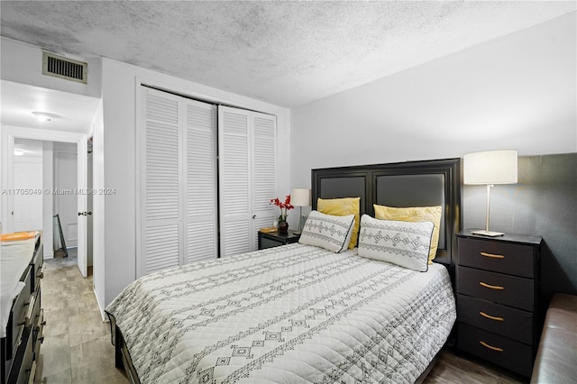 bedroom featuring a textured ceiling, dark hardwood / wood-style floors, and a closet