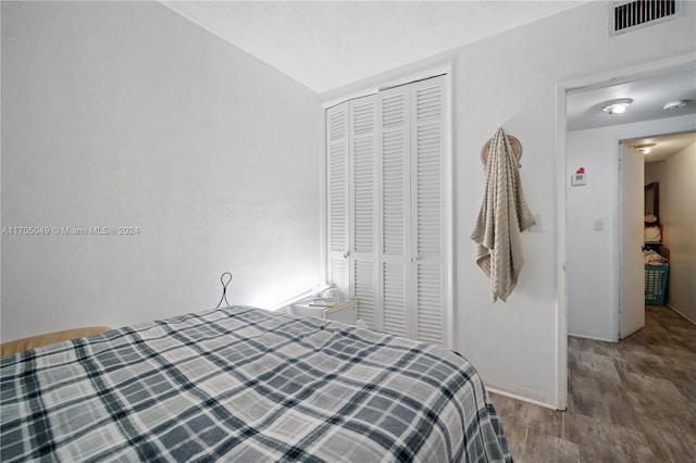 bedroom with hardwood / wood-style flooring, a closet, and lofted ceiling