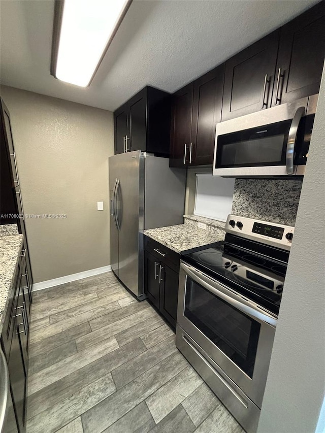 kitchen featuring light stone counters, a textured ceiling, and appliances with stainless steel finishes