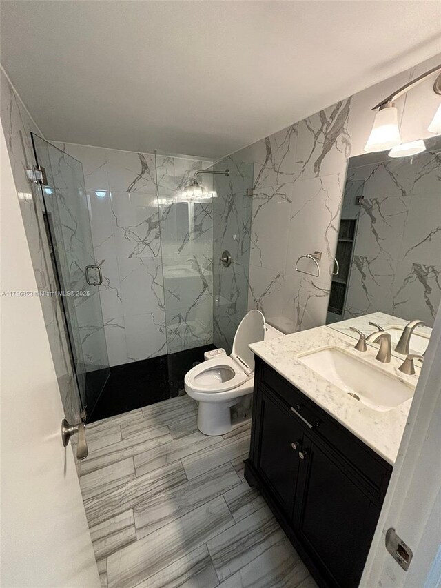 bathroom featuring a shower with shower door, toilet, and vanity