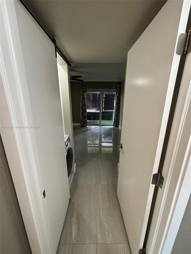 hall with a barn door and washer / dryer