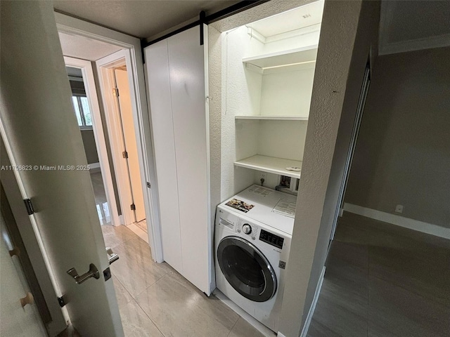 laundry room featuring washer / dryer, light tile patterned floors, and a barn door