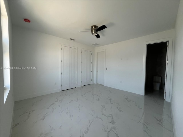 unfurnished bedroom featuring ceiling fan and multiple closets