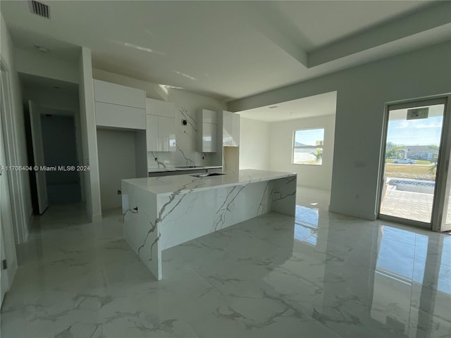 kitchen featuring white cabinetry and light stone countertops