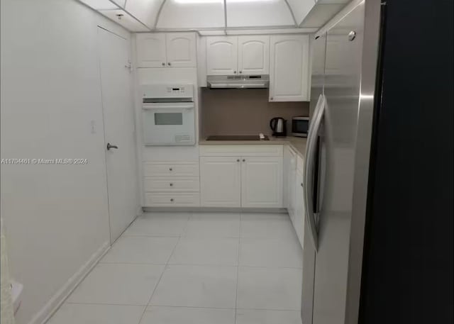 kitchen with light tile patterned floors, stainless steel appliances, and white cabinetry